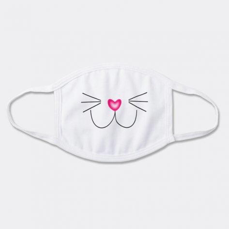 A white face mask with a printed face of a smiling cat, a pink heart nose and whiskers.